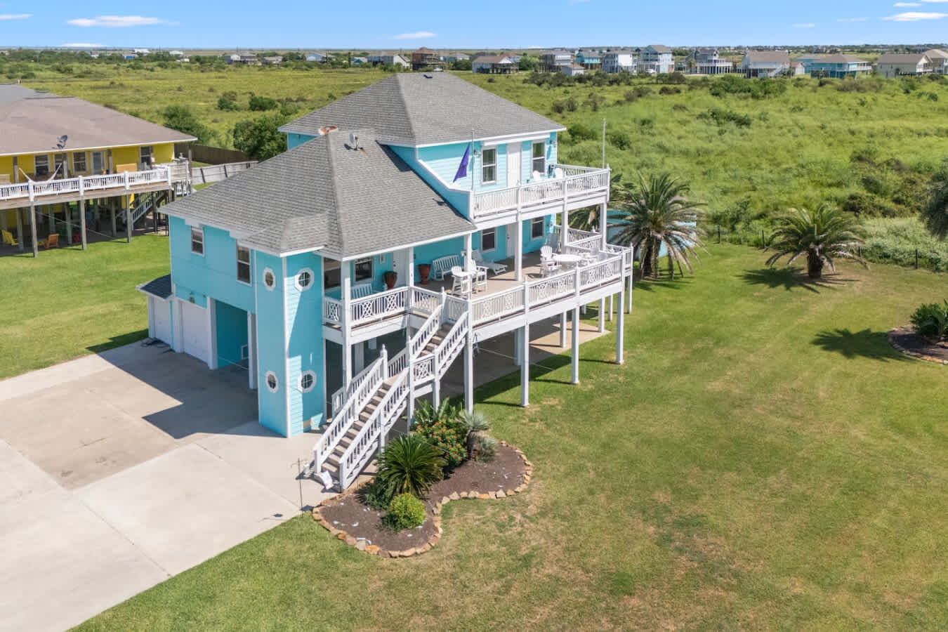 A two-story house with a balcony, a staircase, and a well-maintained lawn.
