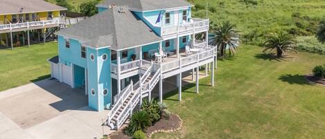 A two-story house with a balcony, a staircase, and a well-maintained lawn.