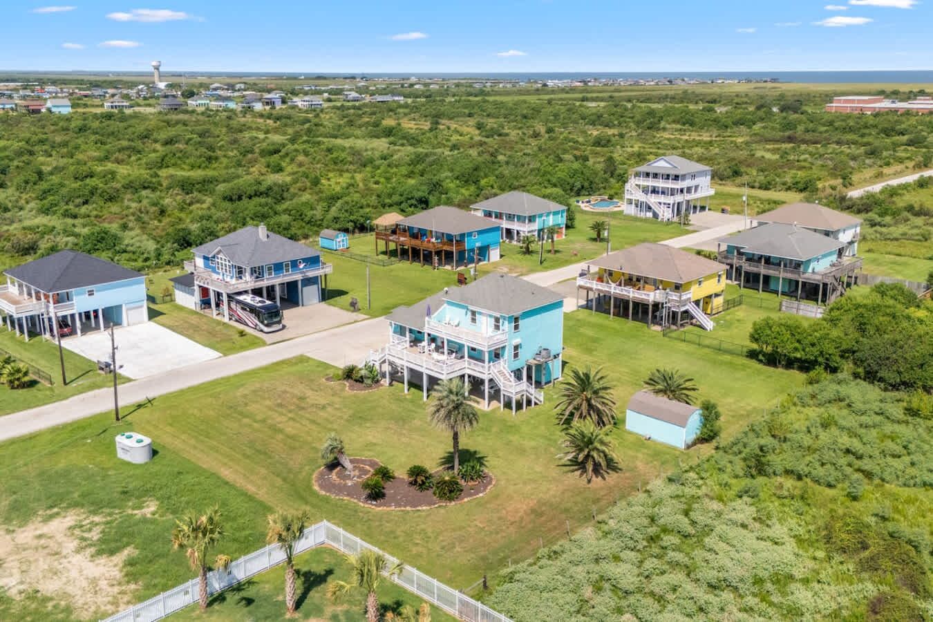 A coastal residential area with houses featuring balconies, a swimming pool, and a clear view of the ocean.