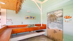 Ein Badezimmer mit einer Holzbank, einem Waschbecken und einem Wandgemälde mit Strandmotiv.
