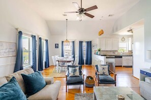 A spacious living room with a sofa, chairs, and a dining area. - 3 King Suites,  15 Guests - Sunzout (Bolivar Peninsula)