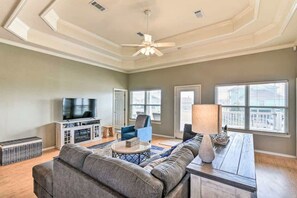 A spacious living room with a large sofa, a television, and a ceiling fan. - Family Retreat, Hangout Garage & Fire Pit, 3Bd 2Bth (Bolivar Peninsula)