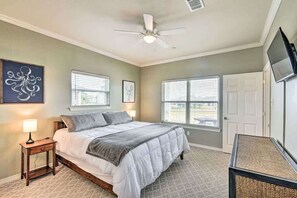 Ein Schlafzimmer mit einem Bett, zwei Nachttischen, einem Deckenventilator und einem Fernseher an der Wand.