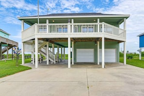 A two-story building with a balcony, a staircase, and a garage. - Family Retreat, Hangout Garage & Fire Pit, 3Bd 2Bth (Bolivar Peninsula)