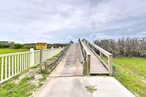 A wooden boardwalk leading to a bridge with a caution sign, surrounded by greenery. - Family Retreat, Hangout Garage & Fire Pit, 3Bd 2Bth (Bolivar Peninsula)