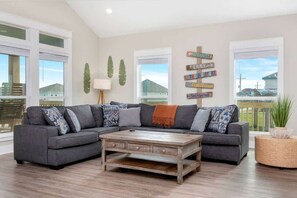 A modern living room with a sectional sofa, a wooden coffee table, and a decorative sign on the wall. - 3 Bdr 3 Bth, King Bed, No Fees (Bolivar Peninsula)