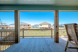 A wooden deck with a view of houses in the background. - 3 Bdr 3 Bth, King Bed, No Fees (Bolivar Peninsula)