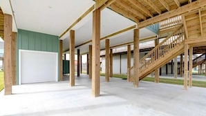 Ein großzügiger Innenbereich mit Betonboden, Holzbalken und einer Treppe.
