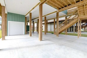 A spacious indoor area with a concrete floor, wooden beams, and a staircase. - 3 Bdr 3 Bth, King Bed, No Fees (Bolivar Peninsula)