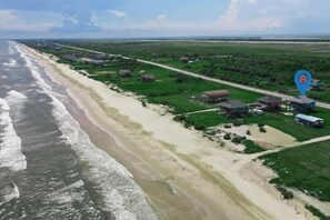 Ein Küstengebiet mit Strand, grünen Feldern und mehreren Gebäuden.