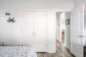 A bedroom with a bed, two white doors, and a hallway leading to another room. - Gulf Views, Steps to Beach, 2 King Beds, 3Bd 2Bth (Bolivar Peninsula)