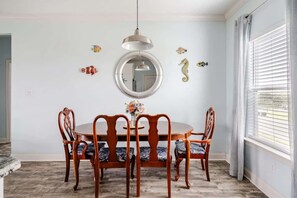 Ein Esszimmer mit einem runden Tisch, vier Stühlen, einer Hängelampe und Wanddekoration.