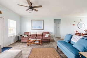 A living room with a ceiling fan, a couch, a coffee table, and a blue sofa. - Gulf Views, Steps to Beach, 2 King Beds, 3Bd 2Bth (Bolivar Peninsula)