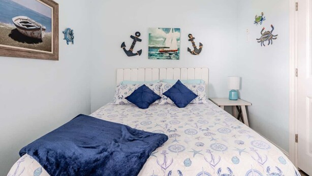 A bedroom with a bed, a nightstand, a lamp, and nautical-themed decorations. - Gulf Views, Steps to Beach, 2 King Beds, 3Bd 2Bth (Bolivar Peninsula)
