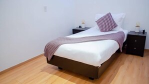 A neatly made bed with a brown headboard, two bedside tables with lamps, and a wooden floor. - Capitalia  Bright & Cozy Family Apt in Santa Fe (Ciudad de México)