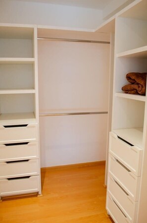 Ein begehbarer Kleiderschrank mit offenen Regalen und Schubladen, Holzboden und Kleiderstange.
