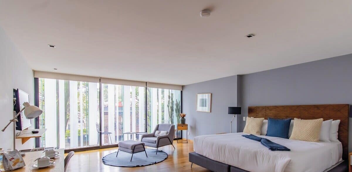 A modern bedroom with a large bed, a desk, and a chair.