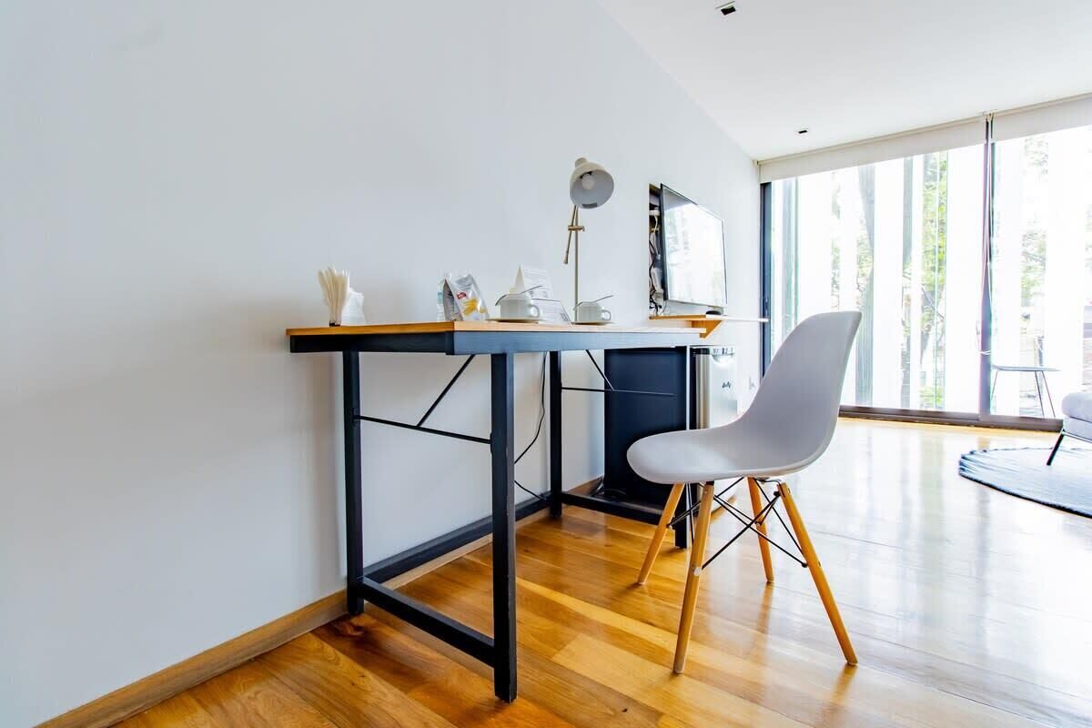A modern office space with a desk, chair, and large windows.