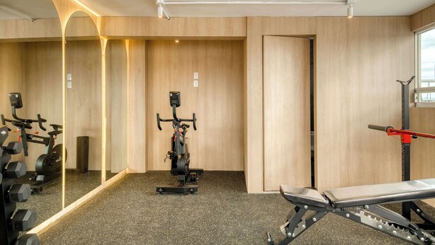 A gym with exercise equipment, a bench press, and a mirrored wall. - Modern King Studio in Central Roma Norte (Ciudad de México)