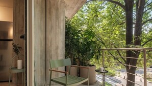 A balcony with a chair, potted plants, and a view of trees. - Modern Loft with Balcony & View of Parque Mexico (Ciudad de México)