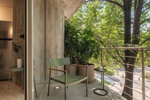 A balcony with a chair, potted plants, and a view of trees. - Modern Loft with Balcony & View of Parque Mexico (Ciudad de México)