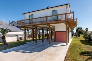 A two-story house with a covered patio area and a red garage door. - 3 Bd 2 5 Bth, King Bed, Pet Friendly (Bolivar Peninsula)