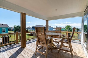 A covered outdoor deck with wooden furniture and a view of residential buildings. - 3 Bd 2 5 Bth, King Bed, Pet Friendly (Bolivar Peninsula)