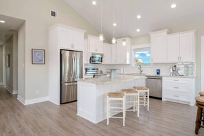 A modern kitchen with white cabinetry, stainless steel appliances, and a central island with bar stools. - 3 Bd 2 5 Bth, King Bed, Pet Friendly (Bolivar Peninsula)