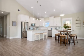 A spacious kitchen with white cabinetry, a central island with stools, stainless steel appliances, and pendant lighting. - 3 Bd 2 5 Bth, King Bed, Pet Friendly (Bolivar Peninsula)
