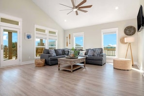 A spacious living room with a ceiling fan, two sofas, a coffee table, and a large window offering a view. - 3 Bd 2 5 Bth, King Bed, Pet Friendly (Bolivar Peninsula)