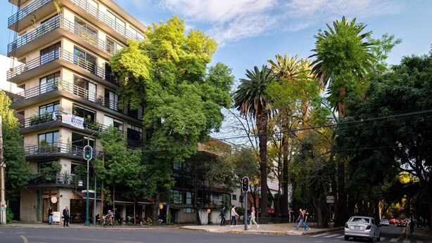 A multi-story building with balconies, surrounded by trees and parked cars. - New 1Bed with Rooftop Terrace Beside Parque Mexico (Ciudad de México)