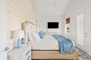 A bedroom with a bed, a TV, a dresser, and a window. - Golf Cart, Elevator, Stylish, 12 guests - LaPerla (Bolivar Peninsula)