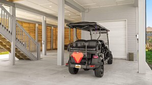 A covered parking area with a golf cart, concrete flooring, and a staircase. - Golf Cart, Elevator, Stylish, 12 guests - LaPerla (Bolivar Peninsula)