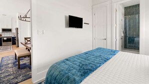 A bedroom with a bed, a television, a door, and a shower area. - Golf Cart, Elevator, Stylish, 12 guests - LaPerla (Bolivar Peninsula)