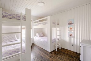 A room with bunk beds, a wooden floor, and a white wall with a star decoration. - 6BR 3Bth Beach House Game Deck, Grill, 26 Guests (Bolivar Peninsula)