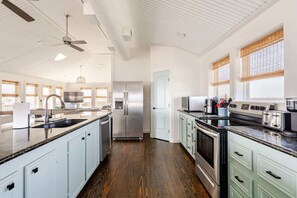 A spacious kitchen with a central island, stainless steel appliances, and a modern design. - 6BR 3Bth Beach House Game Deck, Grill, 26 Guests (Bolivar Peninsula)