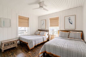 A bedroom with two beds, wooden flooring, and a ceiling fan. - 6BR 3Bth Beach House Game Deck, Grill, 26 Guests (Bolivar Peninsula)