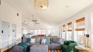 A spacious living area with a large sectional sofa, a colorful rug, and a dining area with a long table.