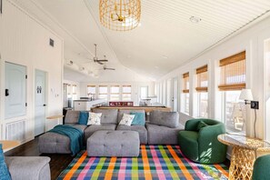A spacious living area with a large sectional sofa, a colorful rug, and a dining area with a long table.