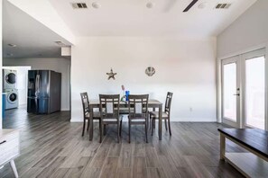 Un coin repas avec une table et des chaises, ainsi qu’un lave-linge et un réfrigérateur en arrière-plan.