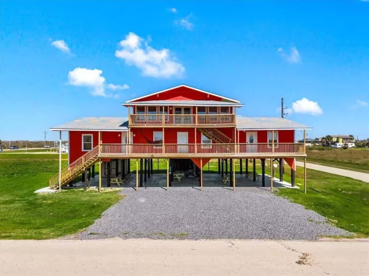 A two-story building with a balcony on the upper floor, a covered front porch, and a gravel driveway.