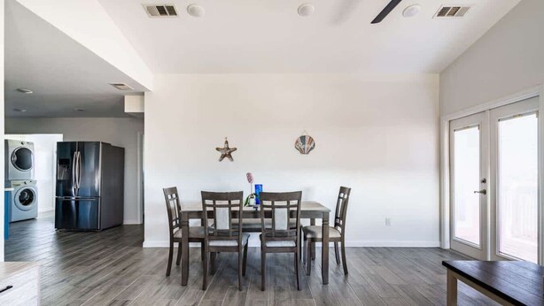 A dining area with a table and chairs, a washing machine, and a refrigerator in the background. - Big 6BR Beach Getaway for 20 Near Ferry, 3 Units (Bolivar Peninsula)