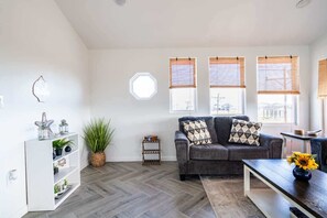 A living room with a grey sofa, a white shelving unit, and a wooden coffee table. - Big 6BR Beach Getaway for 20 Near Ferry, 3 Units (Bolivar Peninsula)