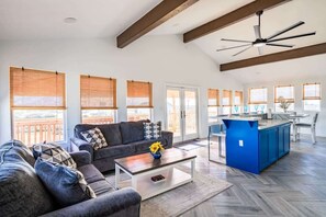 A spacious living area with a sofa, coffee table, and a kitchen area with a blue island and bar stools. - Big 6BR Beach Getaway for 20 Near Ferry, 3 Units (Bolivar Peninsula)