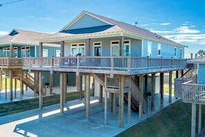 A beachfront house with a wooden deck and a covered outdoor area. - 1 King, 4 Queens, Pet-Friendly (Bolivar Peninsula)