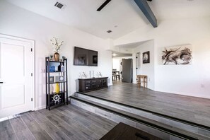 A spacious living area with a dark wood floor, a black entertainment unit, and a dining area with a wooden table and chairs. - Unit A of Crystal Beach's Premier Triplex 2Bd 1Bth (Bolivar Peninsula)