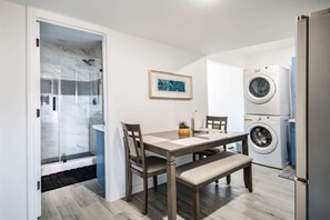 A compact kitchen with a dining area, a washing machine, and a door leading to a bathroom. - Unit A of Crystal Beach's Premier Triplex 2Bd 1Bth (Bolivar Peninsula)