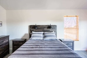 A bedroom with a bed, two bedside tables, a dresser, and a window with a view. - Unit A of Crystal Beach's Premier Triplex 2Bd 1Bth (Bolivar Peninsula)