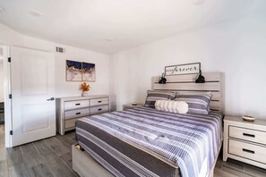 A bedroom with a bed, bedside tables, a dresser, and a wall-mounted artwork. - Unit A of Crystal Beach's Premier Triplex 2Bd 1Bth (Bolivar Peninsula)