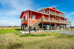 A two-story house with a balcony, wooden deck, and a staircase leading to the upper level. - Unit A of Crystal Beach's Premier Triplex 2Bd 1Bth (Bolivar Peninsula)